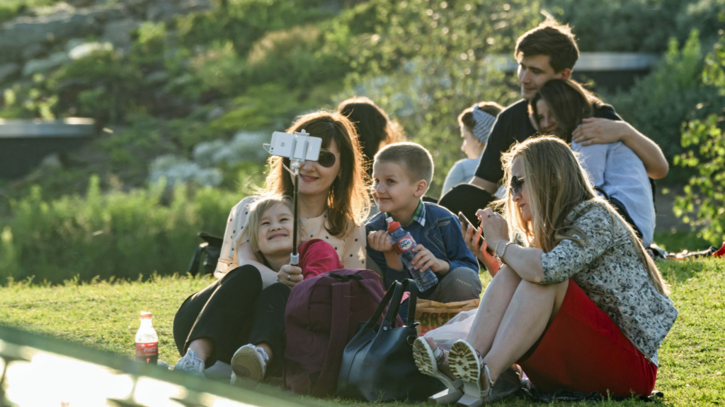 люди делают селфи сидя на газоне